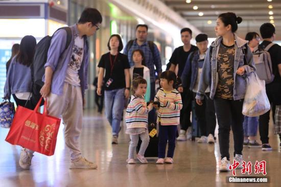 图为两个孩子一起拖着行李箱回家。 殷立勤 摄