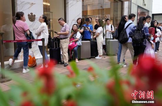 五一假期，香港一家品牌店门口，顾客排起长龙。/p中新社记者 张炜 摄